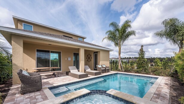 Una casa moderna con piscina, mobiliario exterior y jacuzzi.