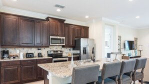 Una cocina moderna con alacenas de madera oscura, electrodomésticos de acero inoxidable, encimeras de granito y una zona de bar con taburetes.