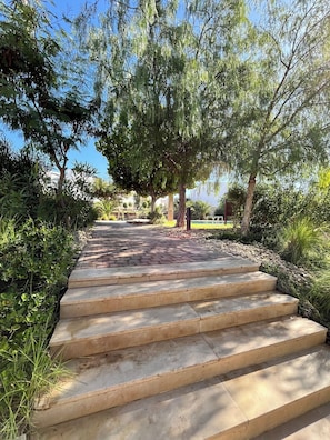 A pathway leading through a garden with steps and trees. - Chic & Cozy One-bedroom apt with 3 beds - Family time in Taghazout (Taghazout)