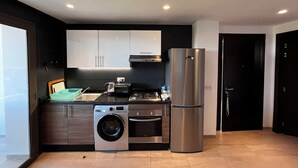 Eine moderne Küche mit einem Edelstahl-Kühlschrank, einer integrierten Waschmaschine und einem Gasherd.