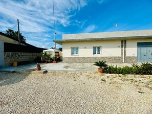 Ein Wohngebiet mit einem Haus, das eine Betonfassade, eine Garage und einen Schotterweg besitzt.