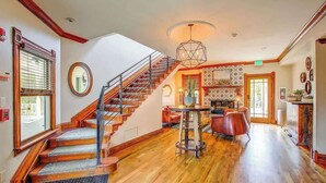 Un interior espacioso con una escalera de madera, una mesa redonda con sillas y una pared decorada.