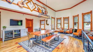 Un salón espacioso con una mesa de comedor de madera, asientos cómodos y un televisor grande.