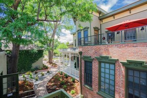 A two-story building with a brick facade, a covered porch, and a red umbrella. - Enchanting Escape | Curtis Park Club Hotel | RiNo (Denver)