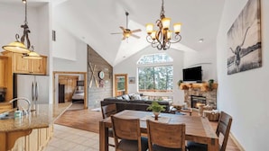 A spacious kitchen with wooden cabinets, a granite countertop, and a dining area with a wooden table and chairs. - Flathead Lodge | Close to Skiing & Glacier Park (Somers)