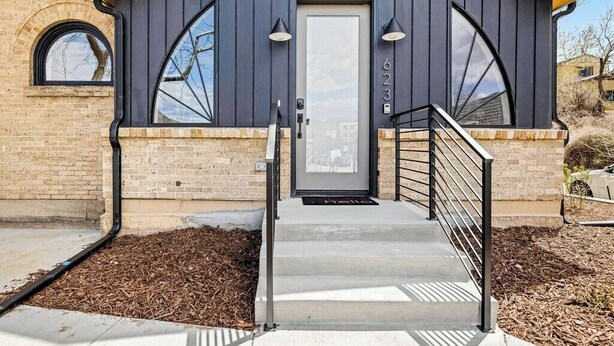 A modern building with a dark facade, a visible door, and a set of concrete steps leading to a metal railing. - The Golden House | 1 Block to Main St (Golden)