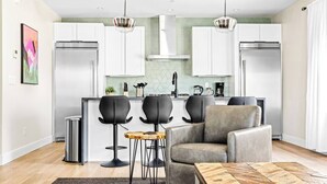 A modern kitchen with white cabinets, a central island, and black bar stools. - The Golden House | 1 Block to Main St (Golden)