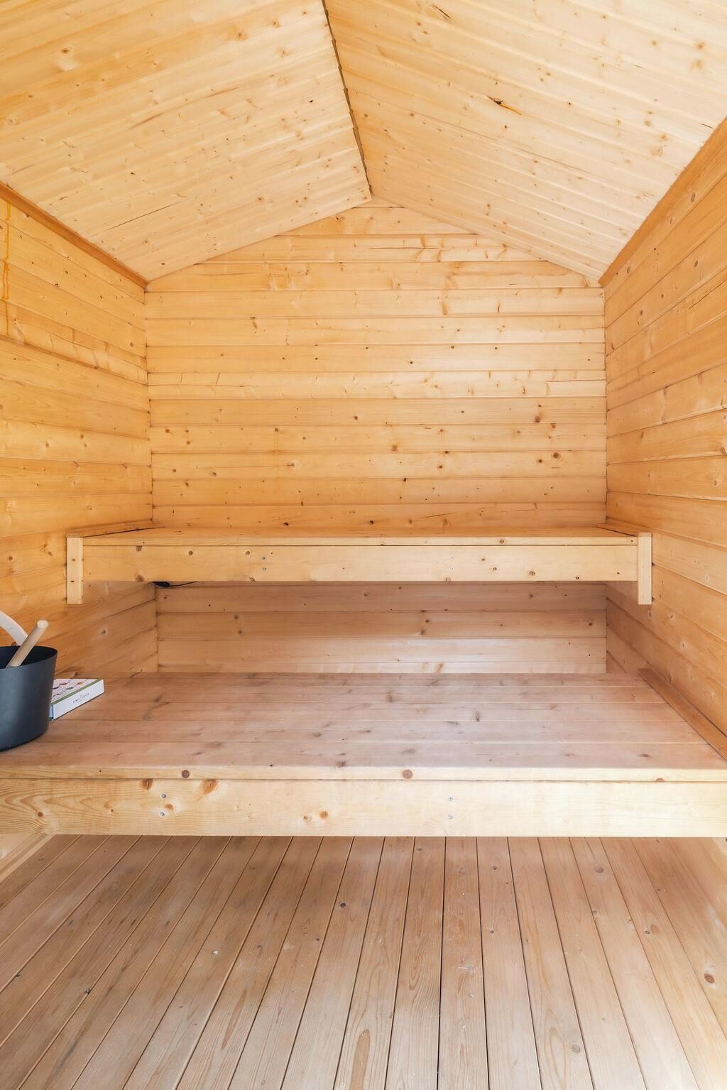 A wooden sauna room with a sloped ceiling and a bench.