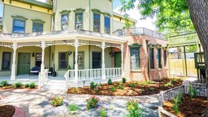 A two-story house with a porch, brick exterior, and a garden with various plants. - Smiths Crescendo | Curtis Park Club Hotel | RiNo (Denver)