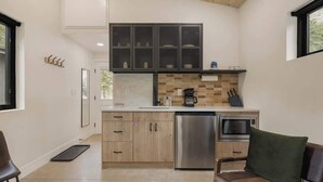 A modern kitchen with a dishwasher, oven, and microwave. There is a wooden ceiling and a window on the right. - Modern Mountain Studio | Hot Tub | Lostfork (Grant)