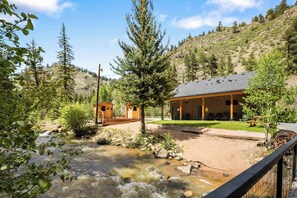 A lodge with a river, wooden cabins, and a mountain backdrop. - Modern Mountain Studio | Hot Tub | Lostfork (Grant)