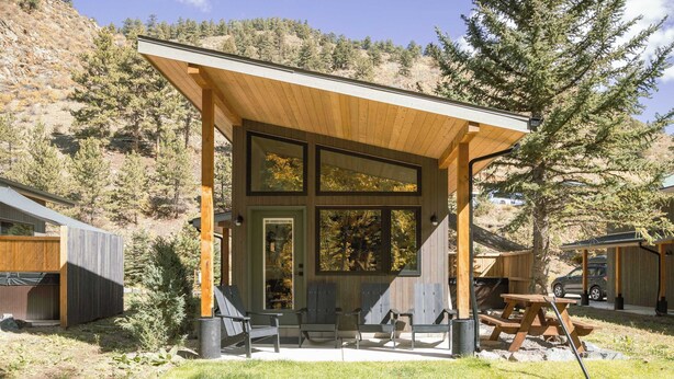 A modern wooden structure with large windows, a covered patio, and a picnic table. - Guanella Studio Cabin | FirePit | Creek | Lostfork (Grant)