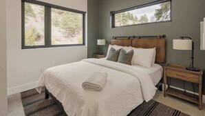 A bedroom with a large bed, two bedside tables, and two windows. - Guanella Cabin Escape | Hot Tub | Sauna | Lostfork (Grant)