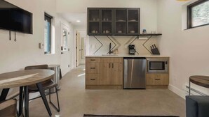 A modern kitchen with wooden cabinets, a stainless steel dishwasher, and a microwave. - Guanella Cabin Escape | Hot Tub | Sauna | Lostfork (Grant)