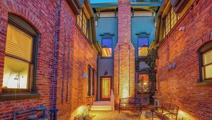 A narrow alleyway with brick buildings, a central brick chimney, and a bench. - Curtis Park Club Hotel | Ultimate Group Retreat (Denver)
