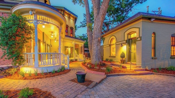 A two-story house with a porch and a well-lit entrance. - Curtis Park Club Hotel | Ultimate Group Retreat (Denver)