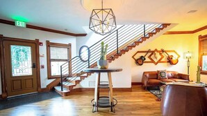 A spacious lobby with a wooden staircase, a round table with a vase, and a brown leather sofa. - Curtis Park Club Hotel | Ultimate Group Retreat (Denver)