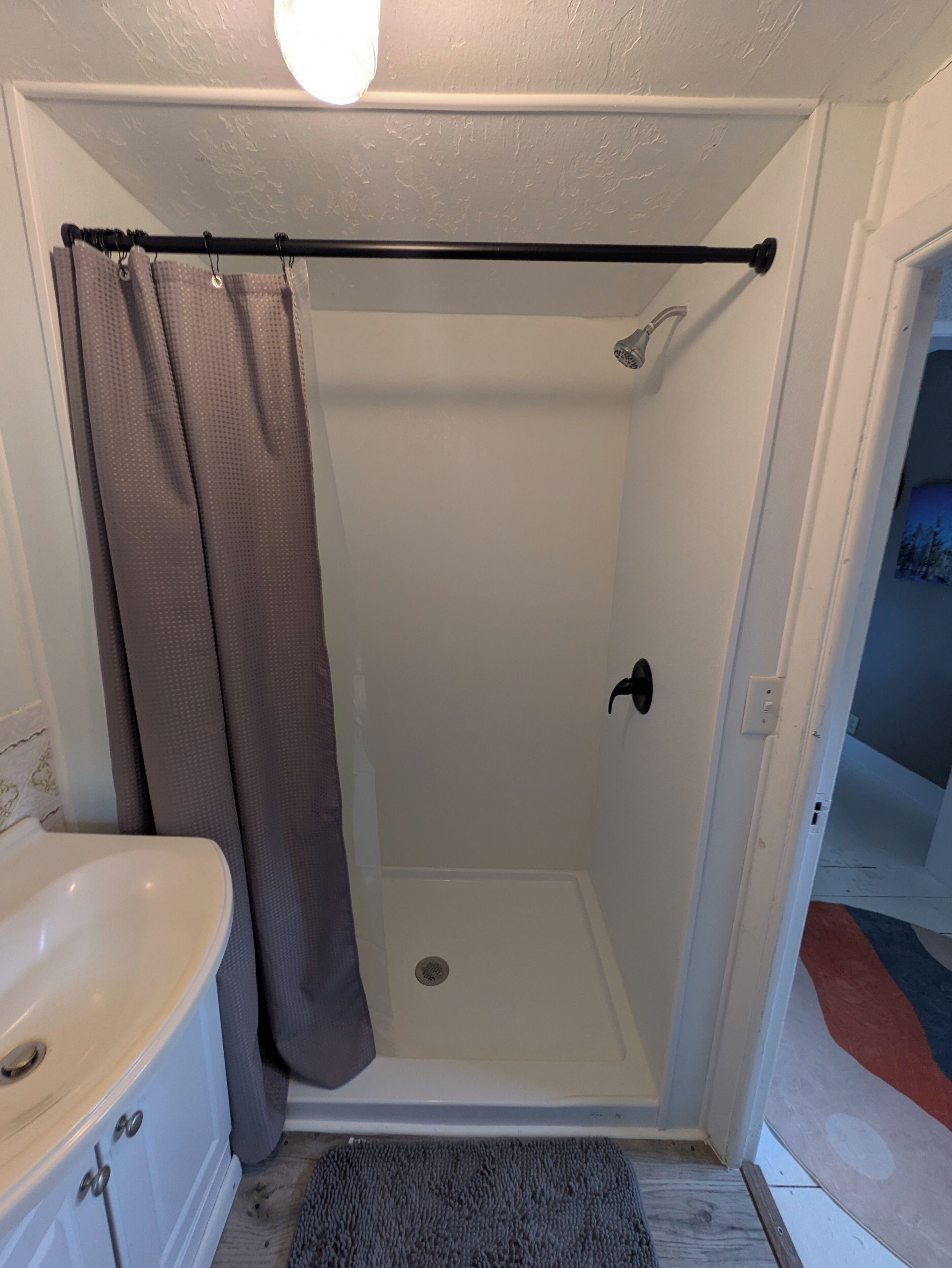 A bathroom with a shower, a bathtub, and a door leading to another room.
