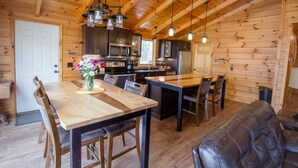 Interior de una cabaña de madera con comedor, cocina y zona de estar.