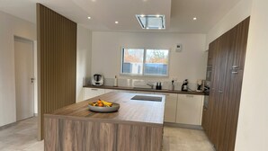A modern kitchen with a central island, a window, and built-in cabinets. - Exceptional villa with indoor pool. beach 300m away, sleeps 14. (Cléder)