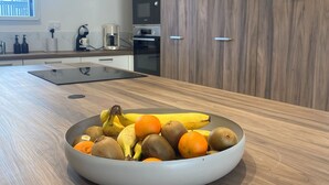 A modern kitchen with a wooden countertop, a bowl of fruit, and built-in appliances. - Exceptional villa with indoor pool. beach 300m away, sleeps 14. (Cléder)