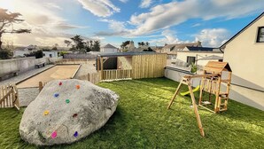 A backyard with a rock, a swing set, and a wooden playhouse. - Exceptional villa with indoor pool. beach 300m away, sleeps 14. (Cléder)