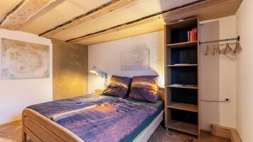 Ein Schlafzimmer mit einem hölzernen Bett, einem Nachttisch, einem Bücherregal und einer Pendelleuchte.