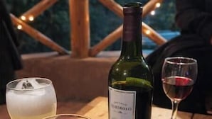 A bottle of wine and two glasses on a wooden table.