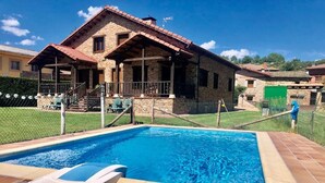 A stone building with a swimming pool, a covered patio, and a fenced area. - Gîte casa lara with swimming pool lagunas (San Martín de valdetuejar)