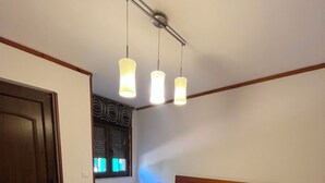 A double bed with a wooden headboard, two bedside tables, a window with blinds, and a ceiling light fixture. - Gîte casa lara with swimming pool lagunas (San Martín de valdetuejar)