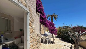 Ein Gebäude mit Steinfassade, Bad, Sitzgelegenheit im Freien und Bougainvillea-Blumen.