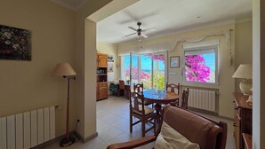 Ein Essbereich mit Tisch und Stühlen, einem Deckenventilator und Blick ins Freie.