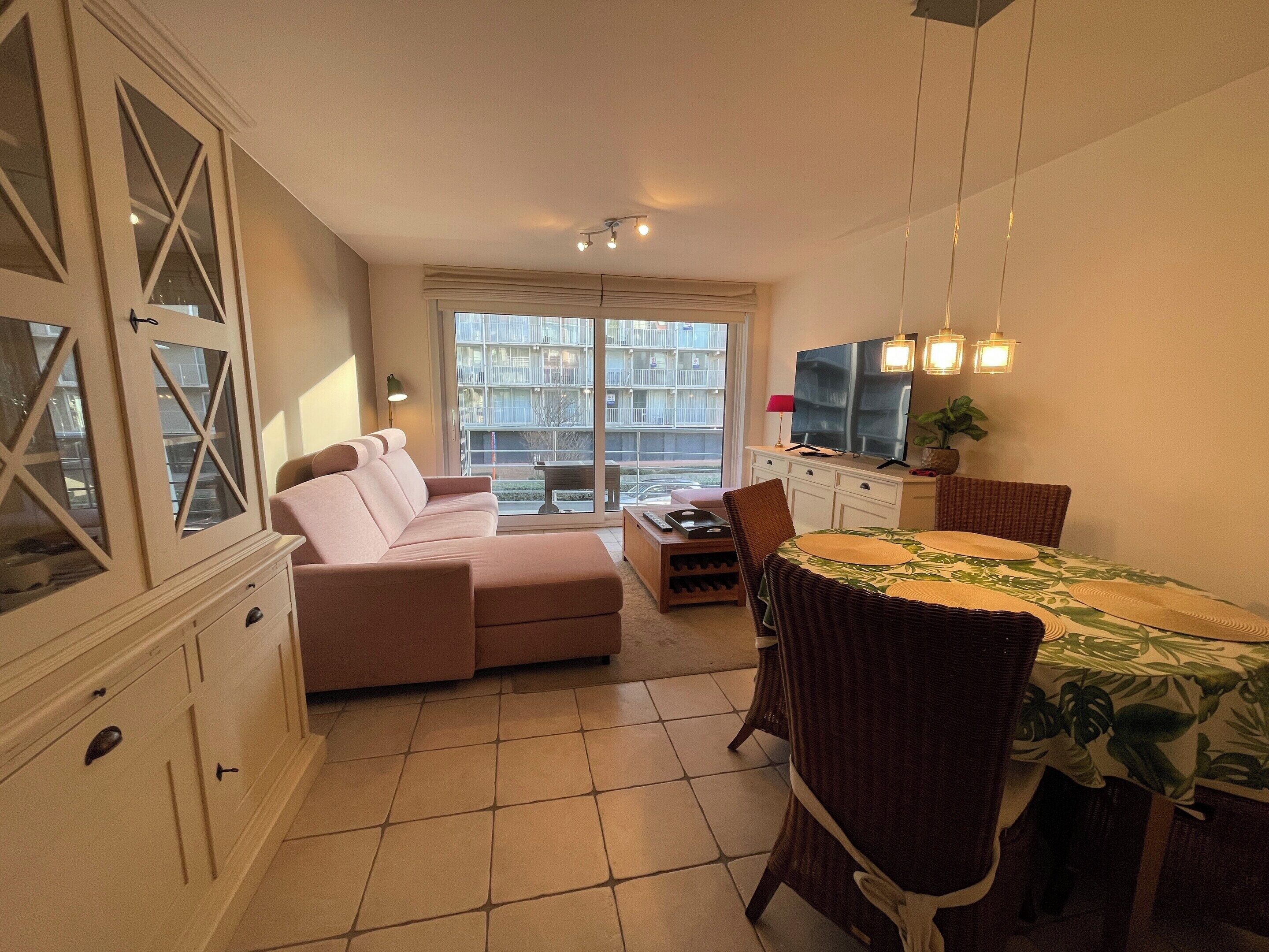 Ein Wohnzimmer mit einer Couch, einem Esstisch, Stühlen und einem Fernseher.