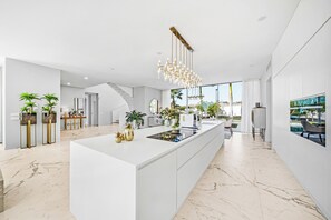 A modern kitchen with a central island, white cabinetry, and a large window providing a view of the outdoors. - Luxury Villa with heated Pool & Jacuzzi Near Costa Adeje Golf (Adeje)