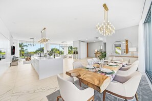 A spacious, modern kitchen with a central island, large windows, and a dining area with a wooden table and white chairs. - Luxury Villa with heated Pool & Jacuzzi Near Costa Adeje Golf (Adeje)