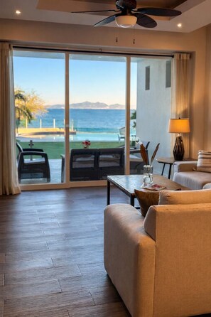 A hotel room with a large sliding glass door leading to a balcony with a view of the ocean.