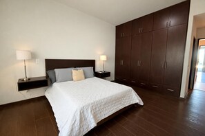 Ein Schlafzimmer mit einem großen Bett, zwei Nachttischen mit Lampen und einem Kleiderschrank.