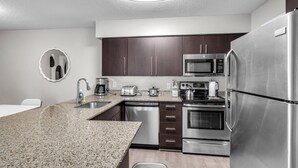 Una cocina moderna con armarios de madera oscura, electrodomésticos de acero inoxidable, encimeras de granito y horno empotrado.