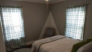 A bedroom with a bed, a chair, and a ceiling fan.