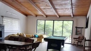 Ein geräumiges Zimmer mit Esstisch, Stühlen, einem Billardtisch und einer Couch.