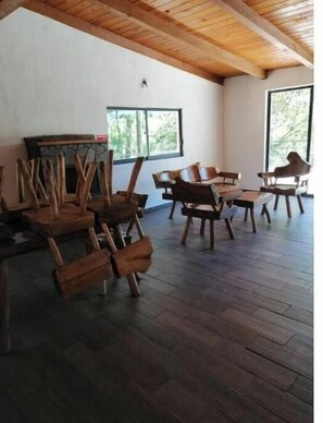 A room with wooden chairs and tables, a fireplace, large windows, and a wooden ceiling. - CABERNET CABANA CABERNET PINOS DEL RIO NEXT TO UMA CACHOEIRA (Mazamitla)