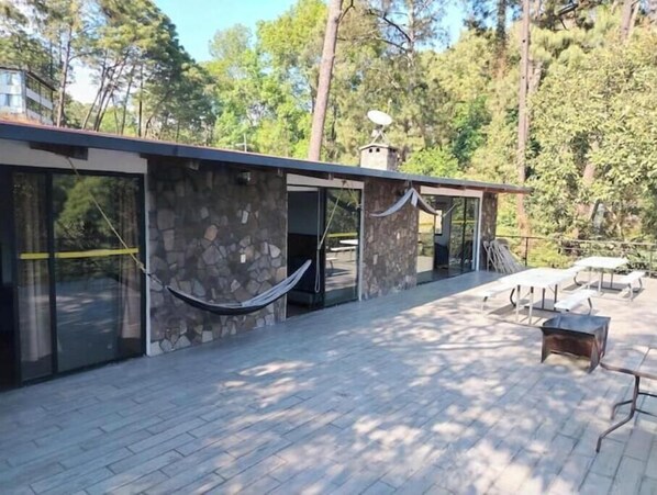 A modern building with stone walls, large glass doors, and a hammock. - CABERNET CABANA CABERNET PINOS DEL RIO NEXT TO UMA CACHOEIRA (Mazamitla)