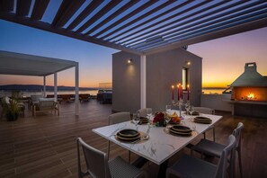 An outdoor dining area with a table set for two, overlooking a body of water at sunset. - Luxury Villa Prime Luna with Heated Pool (Kaštel Sućurac)