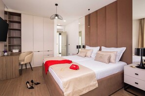 A modern hotel room with a large bed, a desk with a chair, a TV, and a wardrobe. - Luxury Villa Prime Luna with Heated Pool (Kaštel Sućurac)