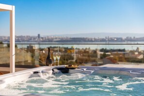 A hot tub with a city view, two glasses of champagne, and a bottle on a balcony. - Luxury Villa Prime Luna with Heated Pool (Kaštel Sućurac)