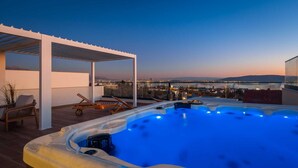 A rooftop terrace with a hot tub, lounge chairs, and a view of the city at dusk. - Luxury Villa Prime Dalia with Heated Pool (Kaštel Sućurac)