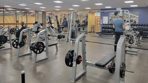 Een sportschool met gewichthefapparatuur, spiegels en diverse trainingsapparaten.