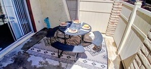 A small outdoor patio with a round table and four chairs, a patterned rug, and a sliding glass door. - Delightful Del Oro/Airpt, Convention & Strip close (Las Vegas)