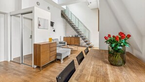 A modern living space with a dining area, a staircase, and a view of the sky.