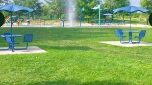 A park with green grass, blue benches, and a fountain. - Serene Lake Ontario Retreat • Entire Home Near Trails & Beach. (Ajax)